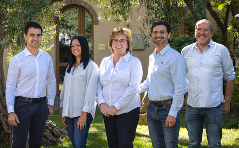 A landscape picture of The Pala Team. 5 people are seen smiling at the camera while in front of a winery building.