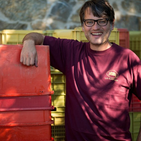A portrait of Riccardo Campinoti smiling while leaning on red crates.